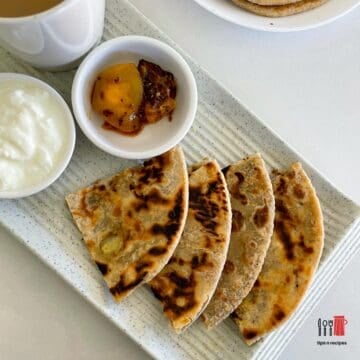 stuffed paratha cut into triangles served on a platter.