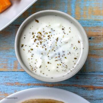 Bowl of all purpose dip served with vegetables and paratha.