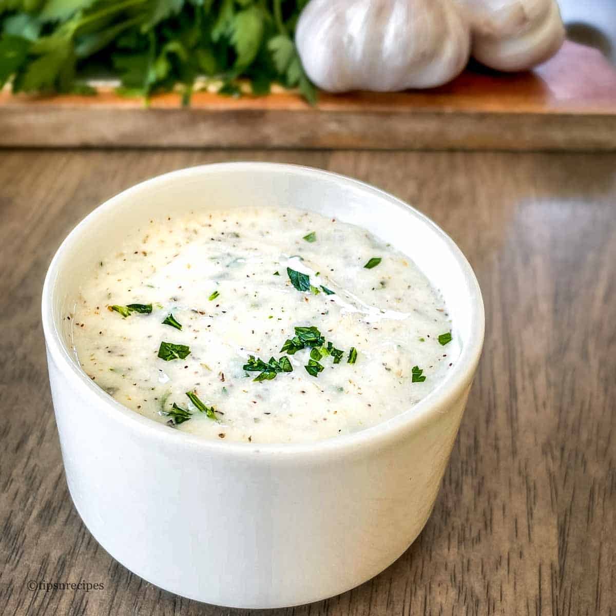 A white bowl of herb and garlic dip.