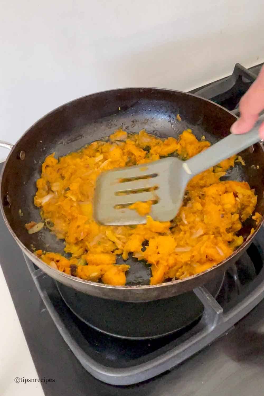 Mashing of pumpkin kaddu chunks in a pan.