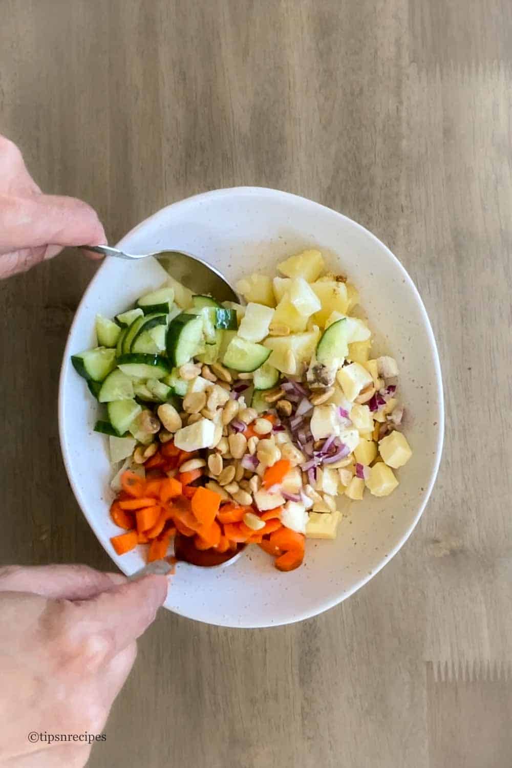 Mixing of salad ingredients in a bowl.