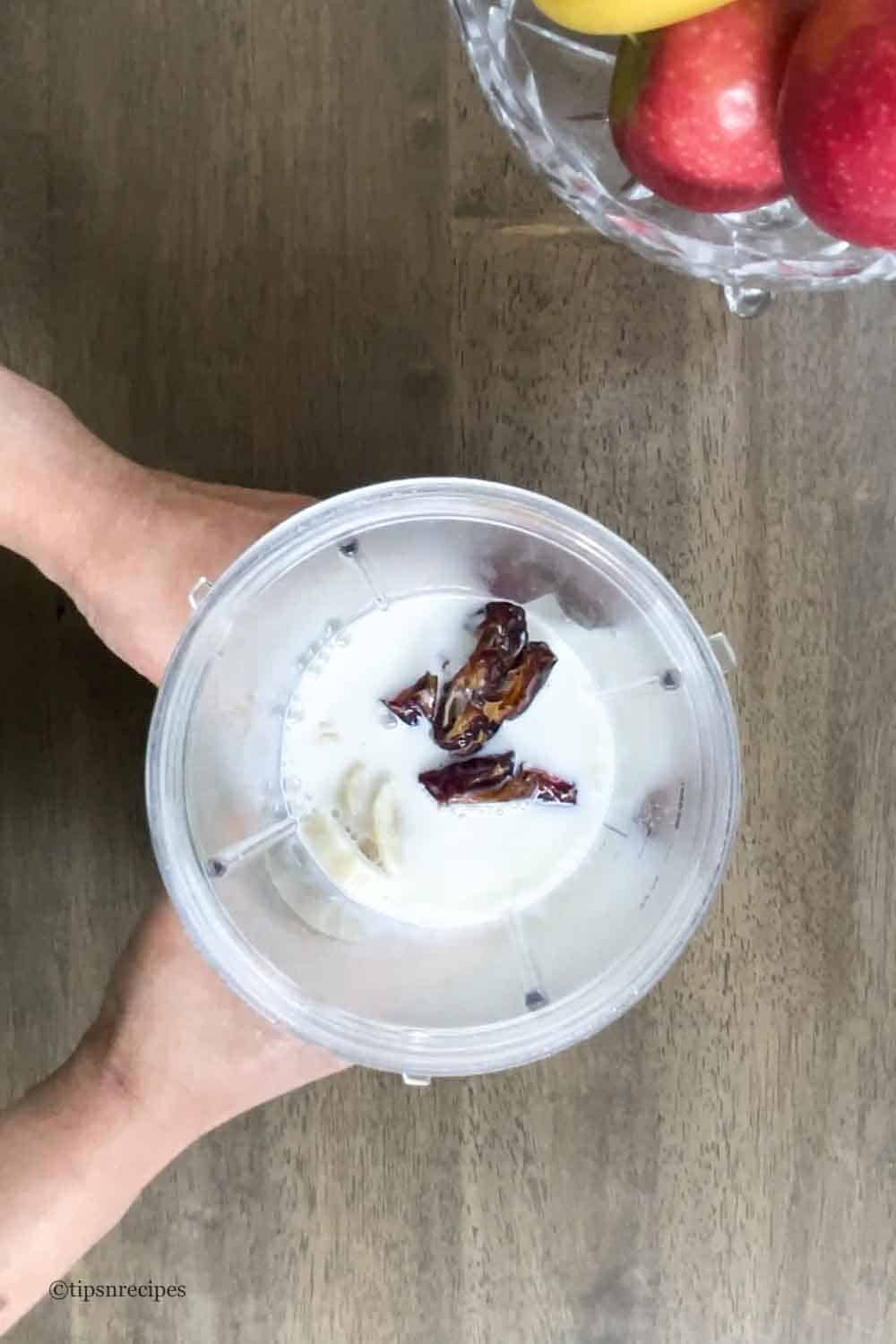 Blending of dates, milk, banana and apple for smoothie.