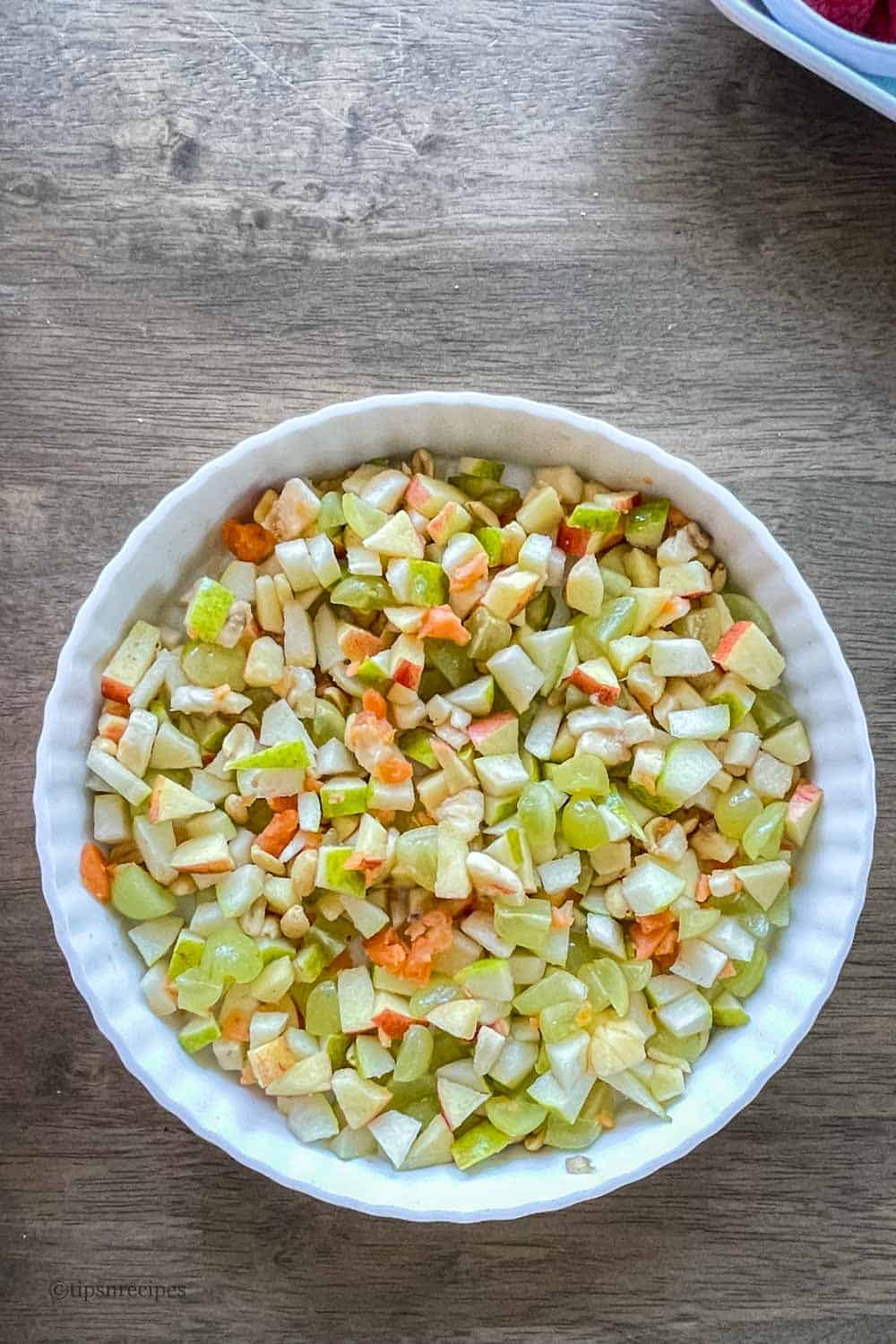 A bowl of freshly cut fruits with roasted nuts to be served as a welcome snack bowl.