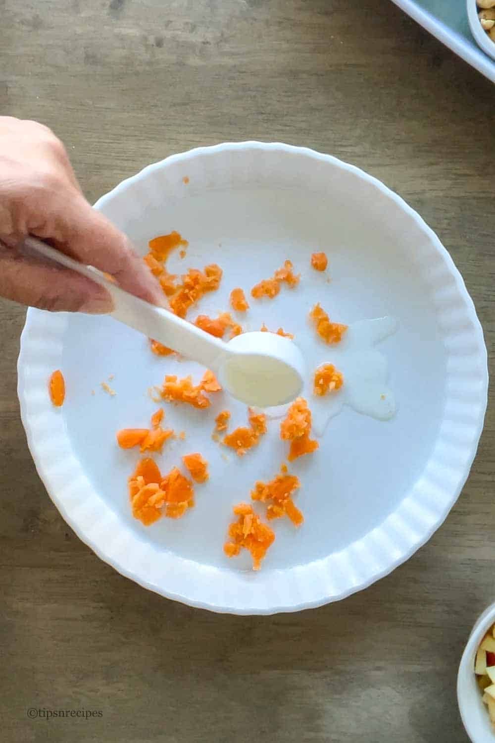 A tablespoon of lemon juice is added to mashed boiled potato into a bowl.