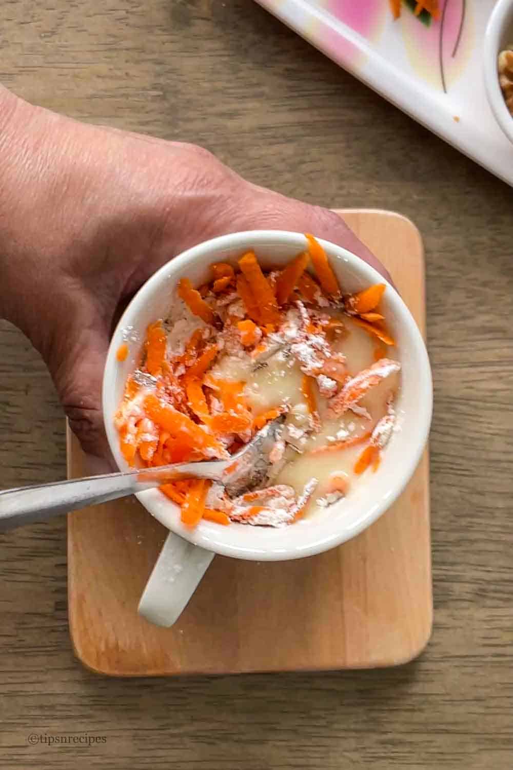 Mixing of all the carrot cake ingredients with a spoon in a mug.