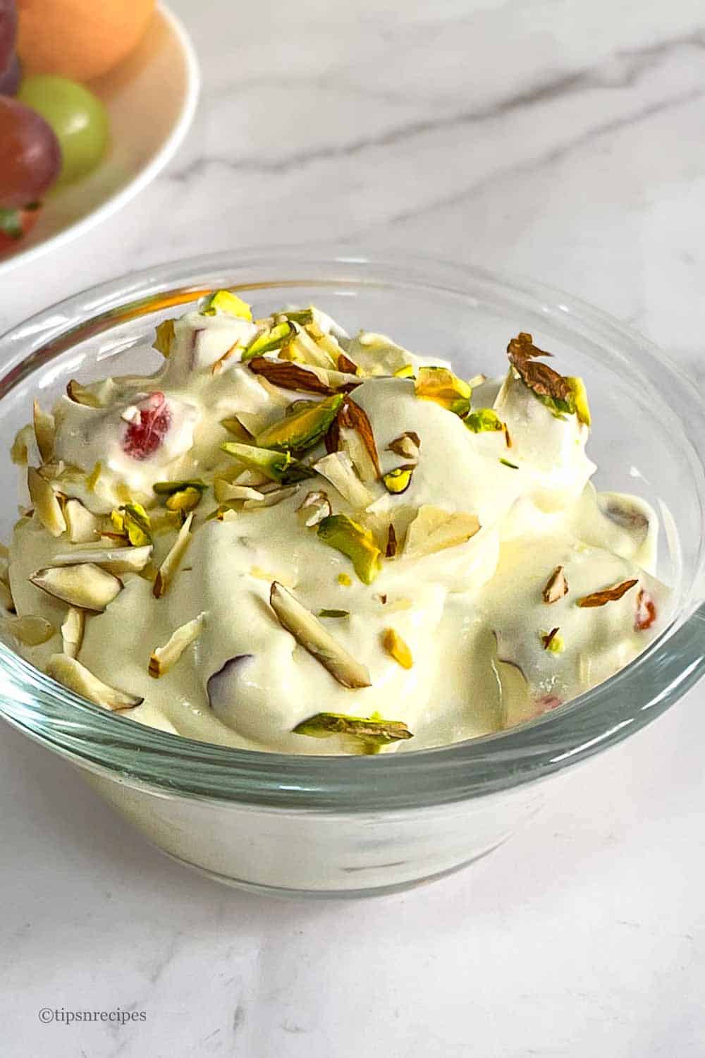 A bowl of fruit cream topped with nuts.