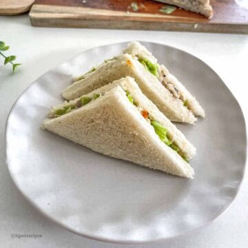 Delicious chicken and lettuce sandwich triangles on a white plate, perfect for lunch or snack.