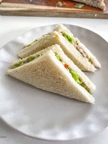 Delicious chicken and lettuce sandwich triangles on a white plate, perfect for lunch or snack.
