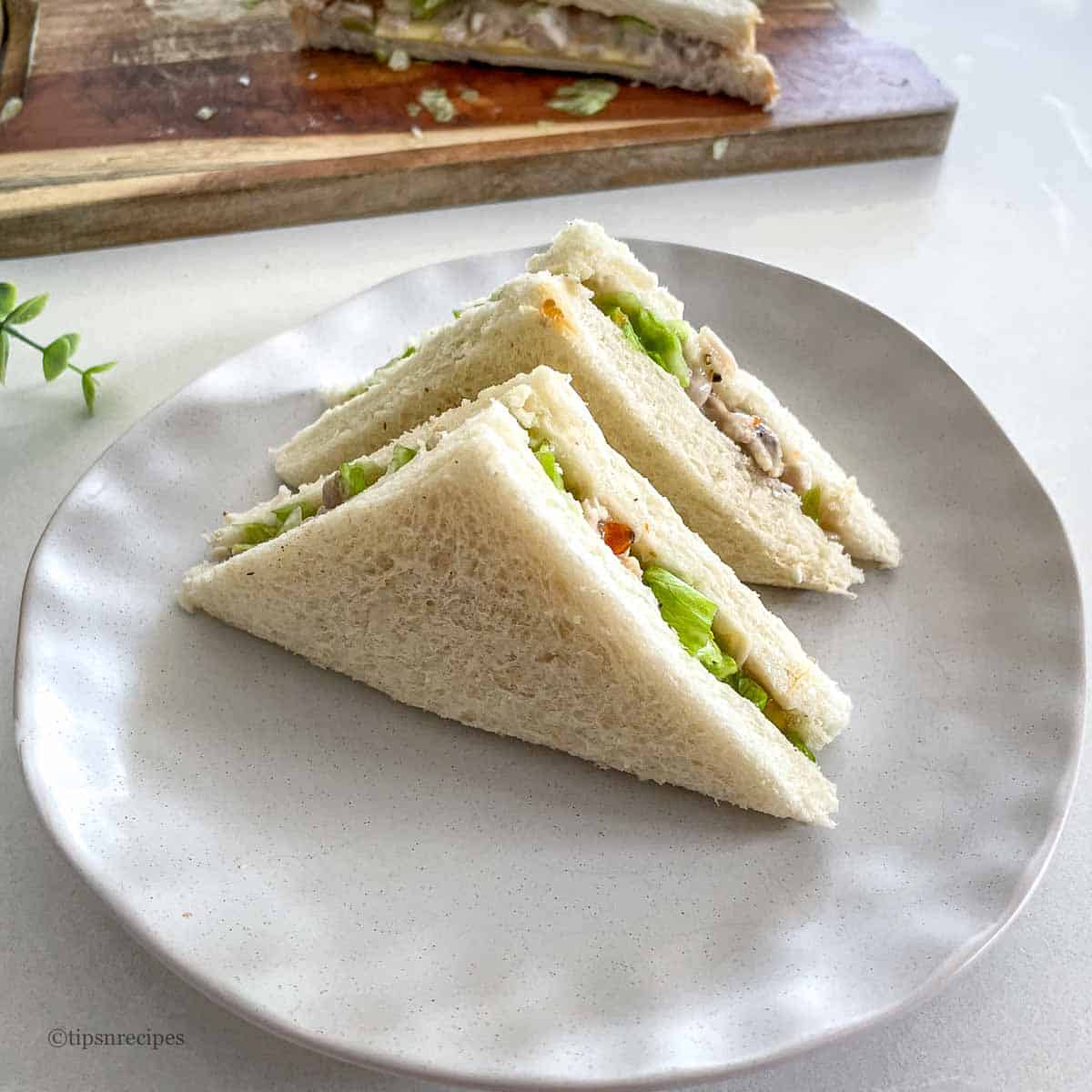 Fresh chicken mayo sandwiches with lettuce served on a white plate.
