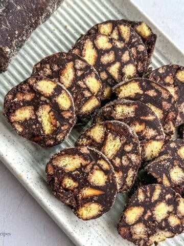 Chocolate biscuit slice with nuts on a white plate.