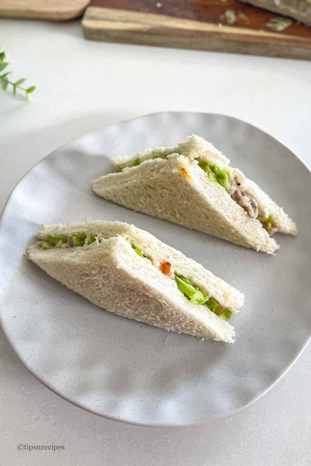 Delicious chicken mayo sandwich triangles on a white plate, perfect for lunch or snack.