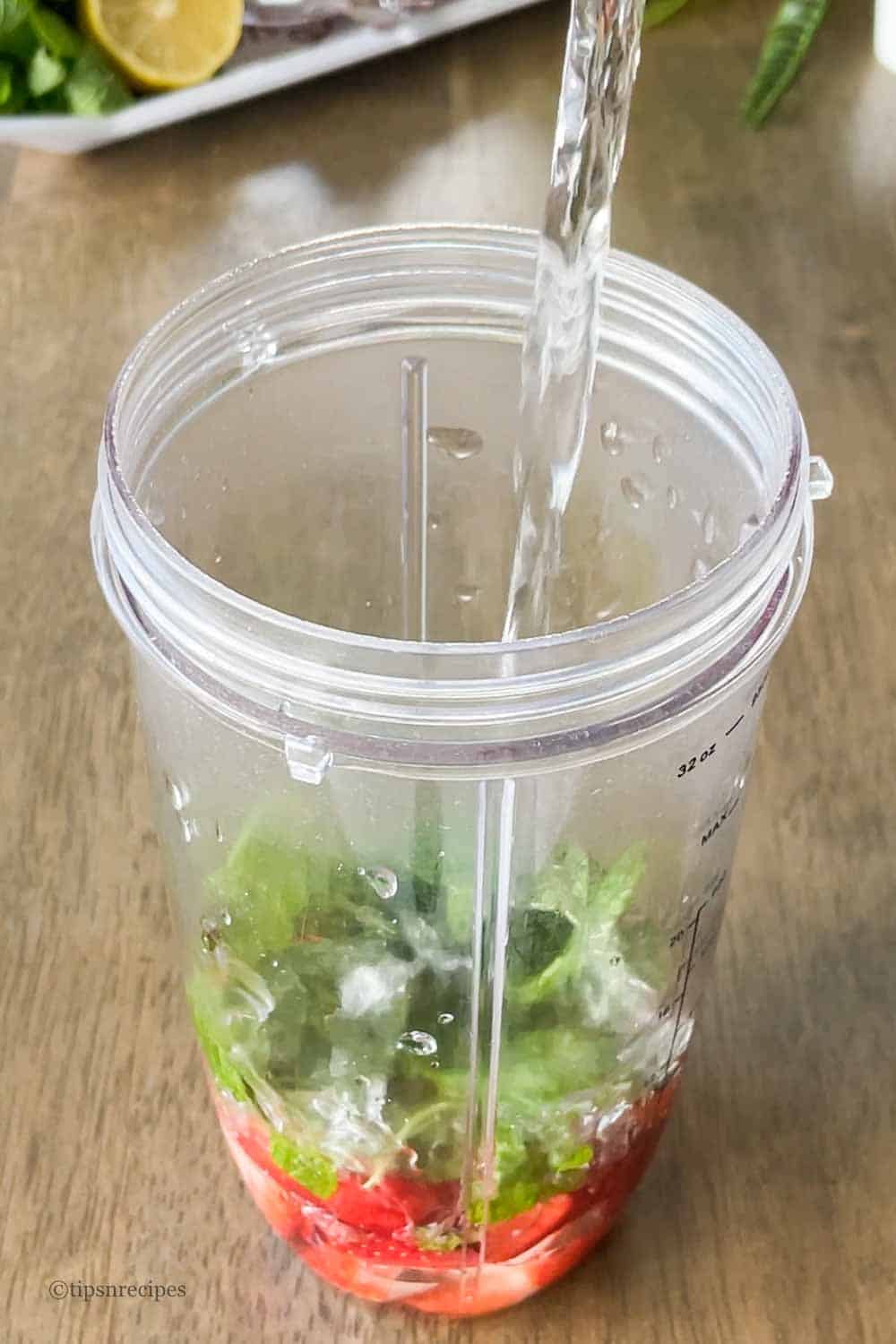 Water added to the blending jar with strawberries, mint and sweetner in the jar.