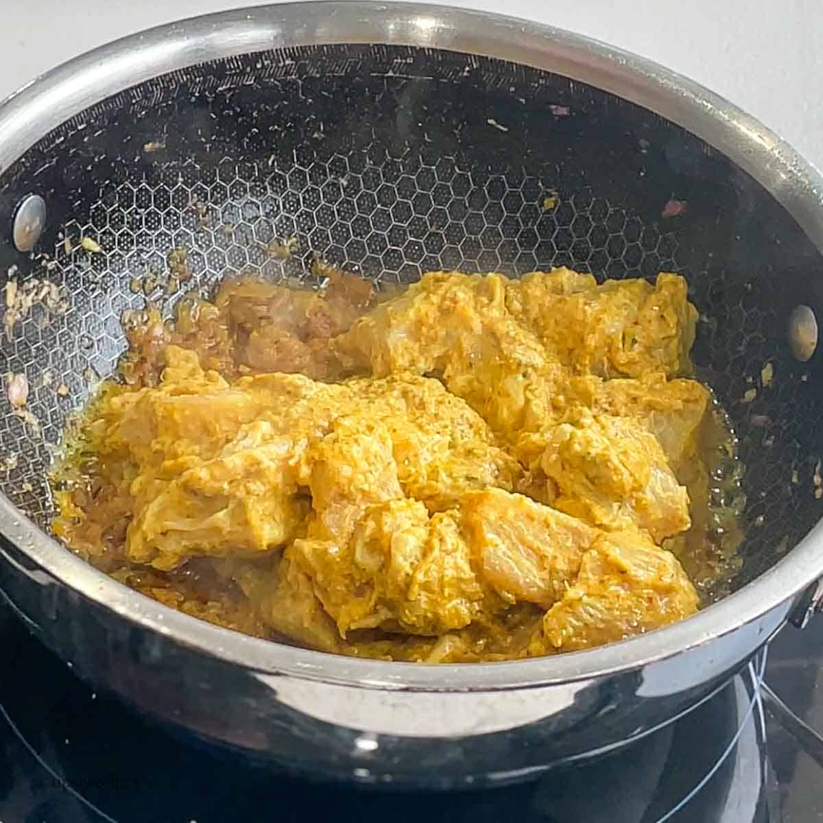 Frying of marinated chicken in butter curry.