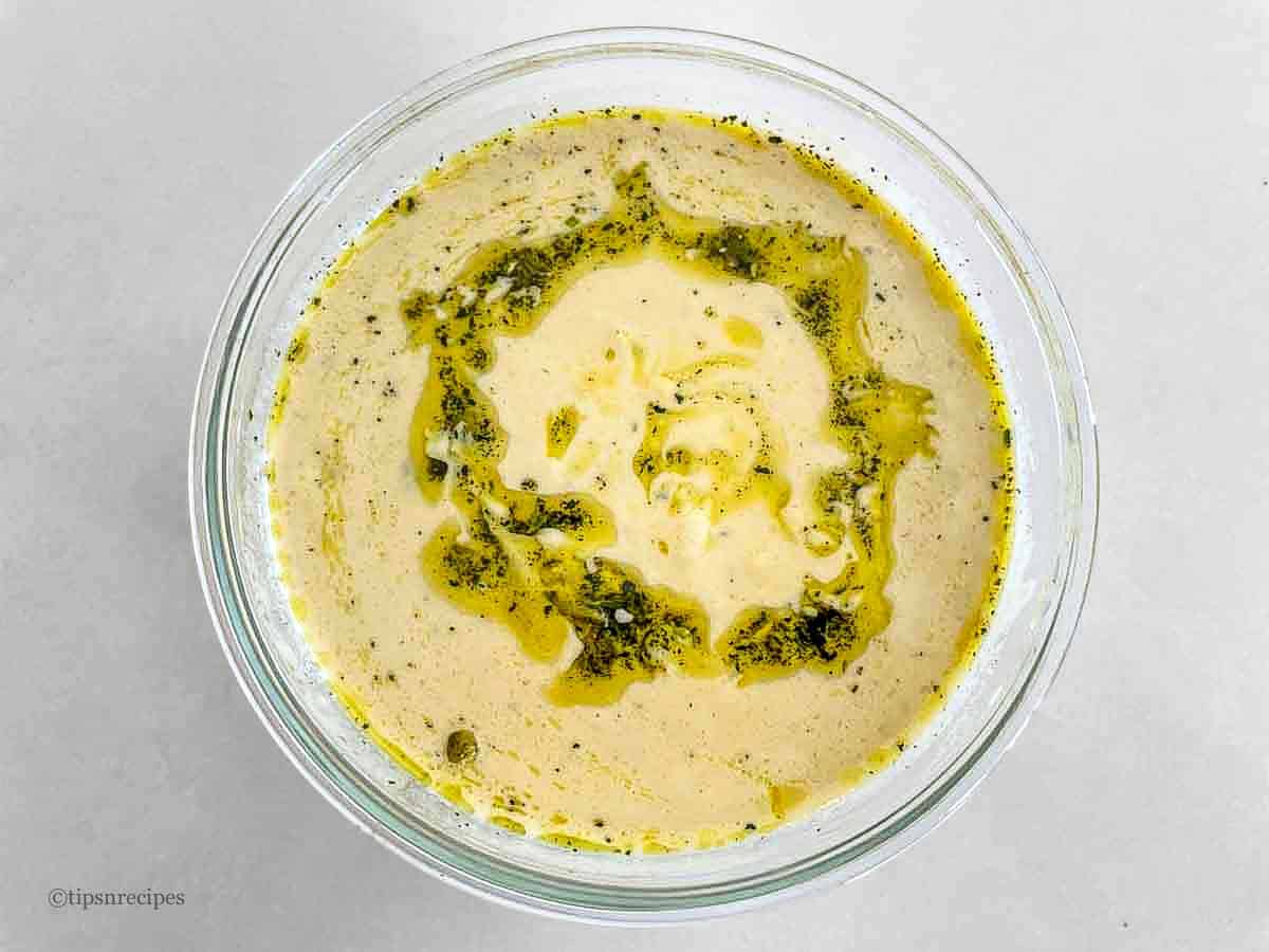 A bowl of high protein hummus with a drizzle of garlic and mint infused oil.