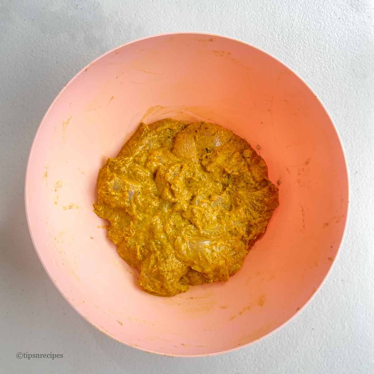 A bowl of chicken marinated in butter, yogurt and spices.