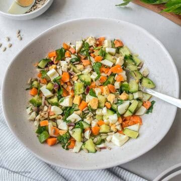 A bowl of boiled eggs and vegetables with a spoon in it.