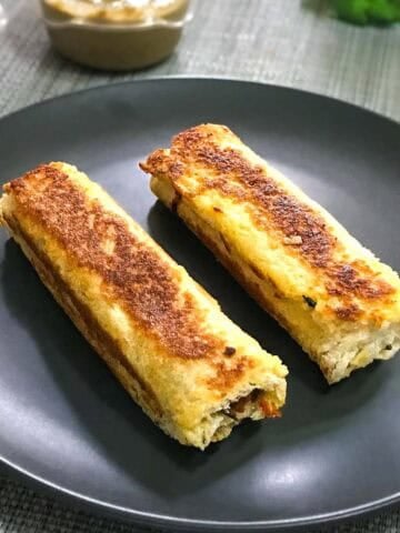 Two golden-brown bread rolls on a black plate.