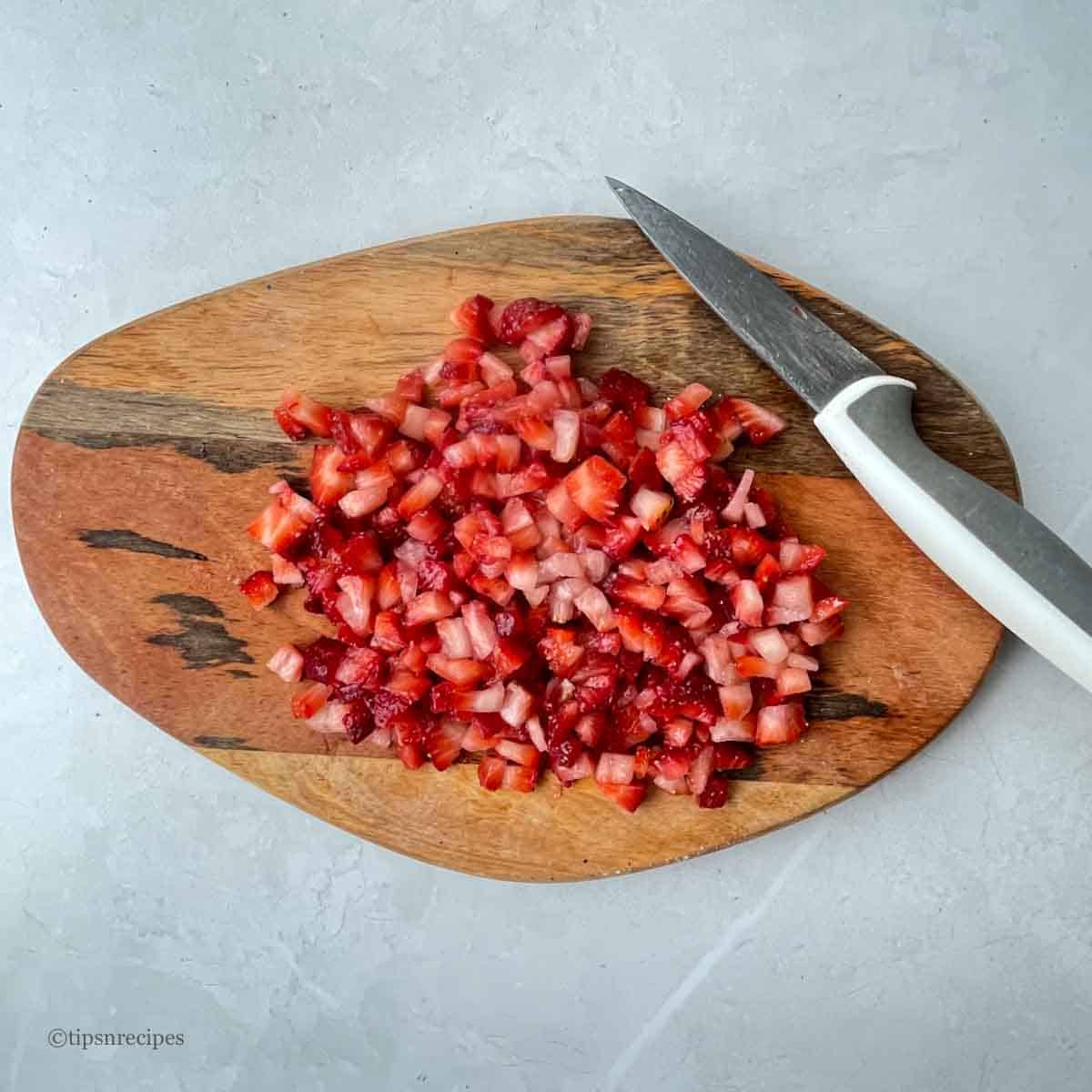 Chopped fresh starwberries with a knife on the chopping board.
