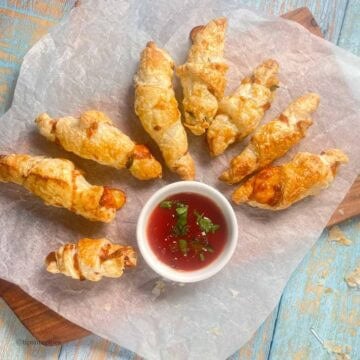 Cheesy buttery mini croissants arranged in a circular motion with a dip on a parchment paper.