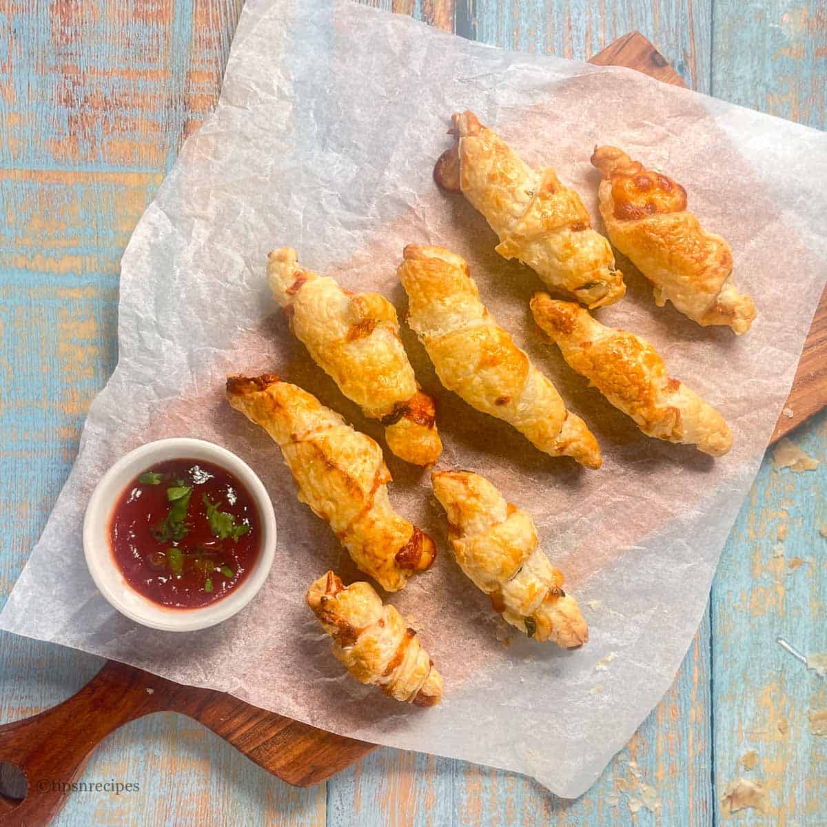 Golden crispy cheesy croissants with dipping sauce on parchment paper.