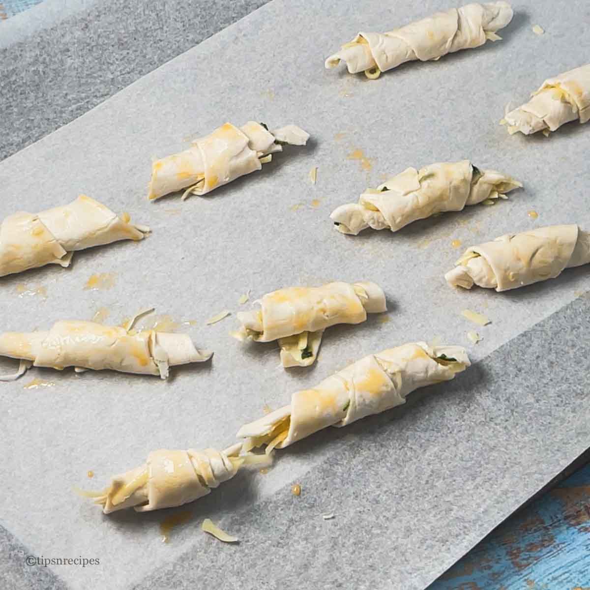 Egg washed mini croissants placed on baking sheet.