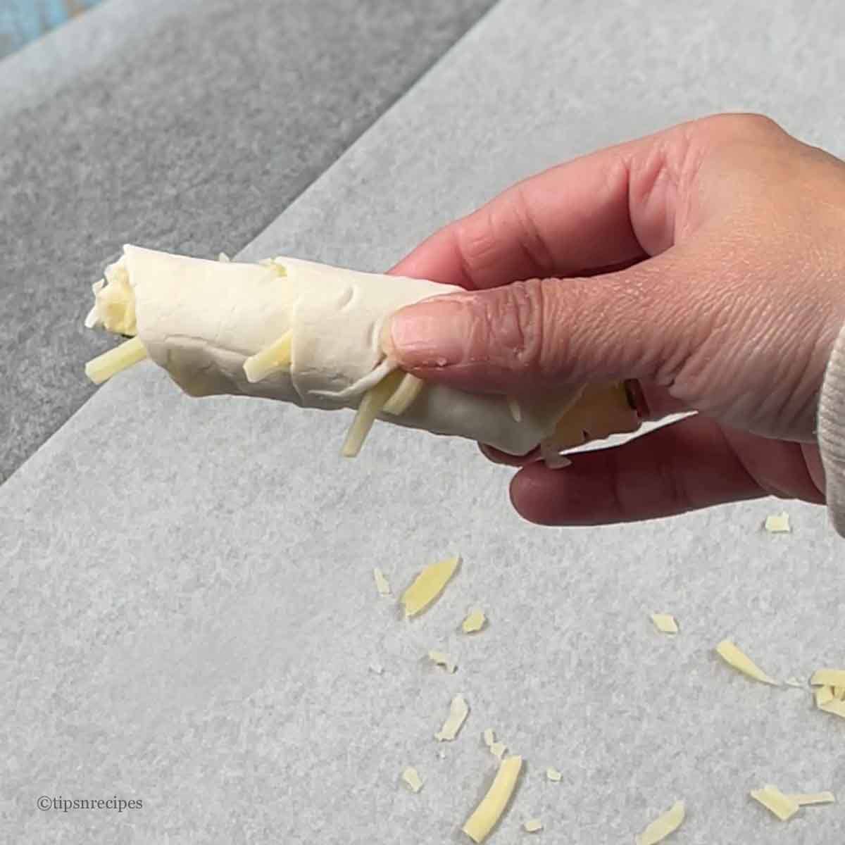 Hand showing the folding of triangles into croissants.