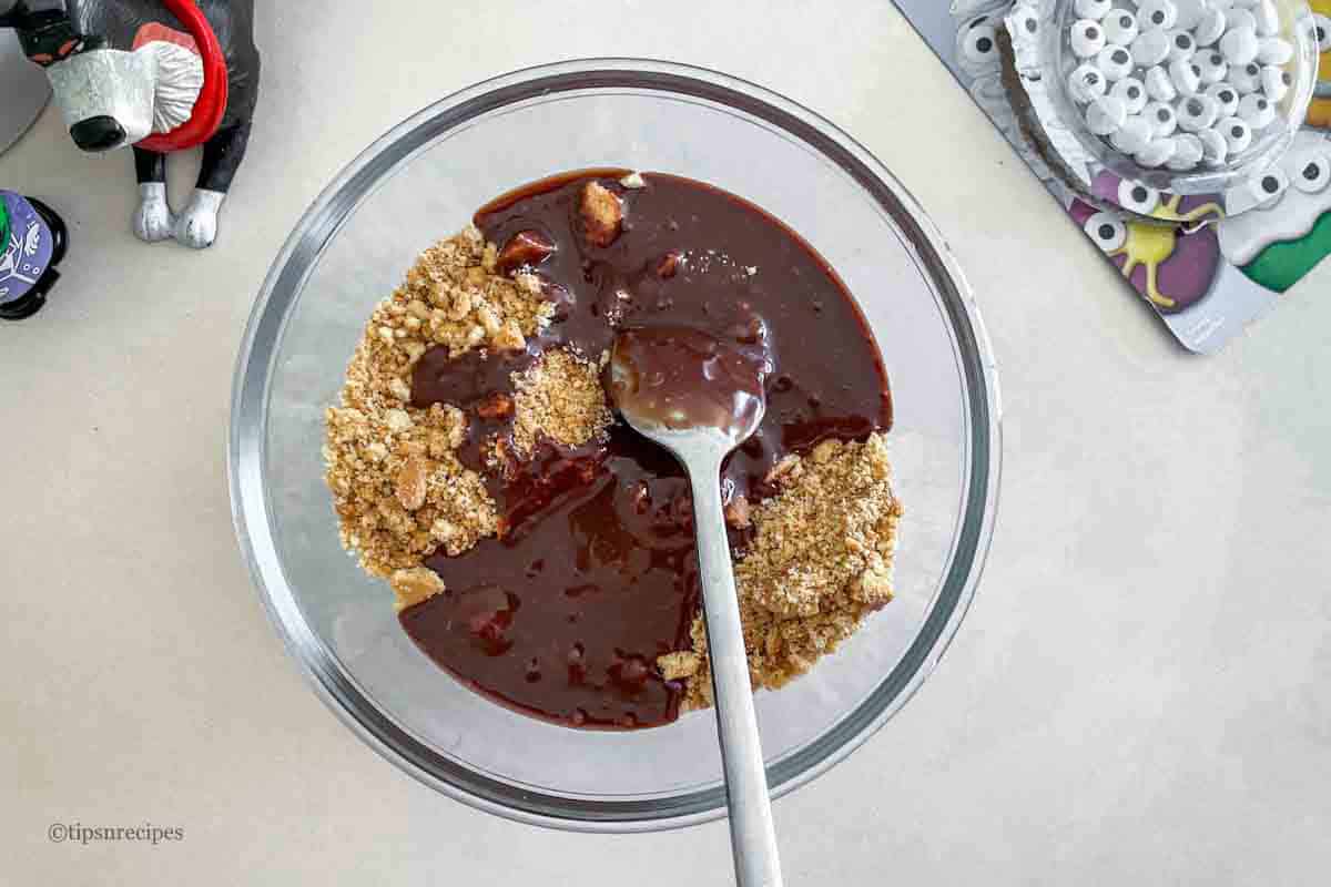 Chocolate cookie mix with a spoon in a glass bowl.