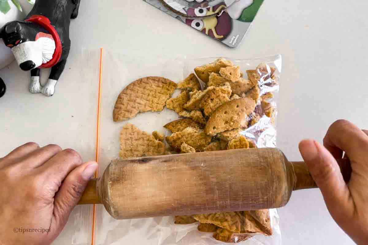 Making cookie crumbs with a rolling pin.